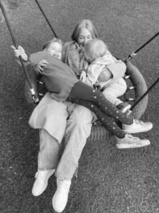 picture of a woman on a swing with young girl and baby boy