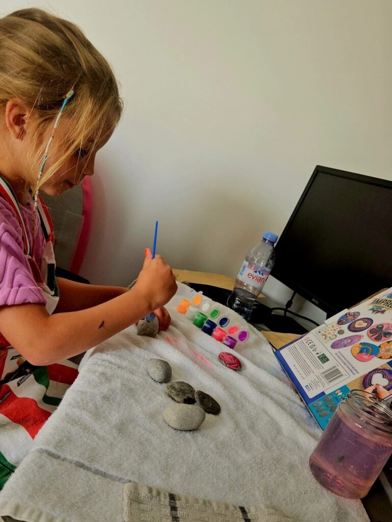 image of young girl painting rocks at computer desk