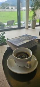 A book and coffee beside the window at Hotel Spirodom in Admont