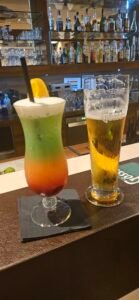 A colourful layered drink and a glass of beer on a bar in Admont