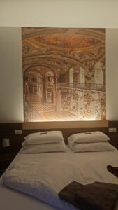 Bed beneath a large picture of Admont Abbey Library at Hotel Spirodom